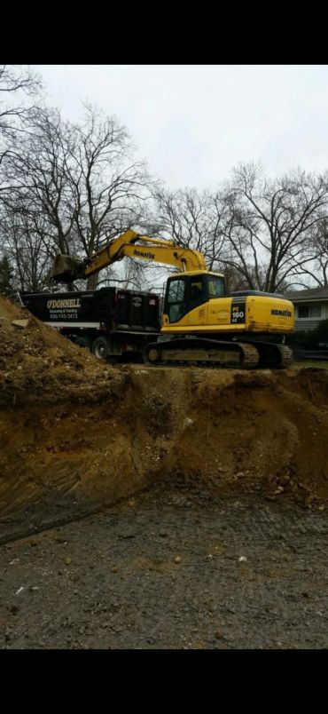 Yellow excavator loading soil into truck at construction site.