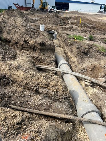 Trenches with large drainage pipes at a construction site.