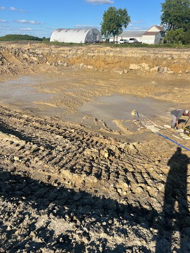 Excavation site with muddy ground and a worker.