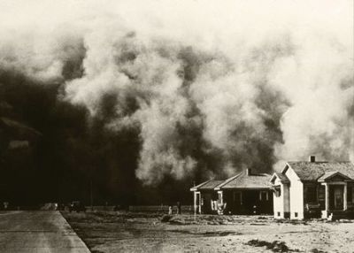 A massive dust storm approaches houses.