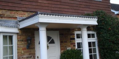 Entrance of a brick house with white columns and a white door.
