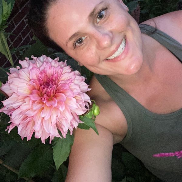 A woman smiling with a big dahlia.