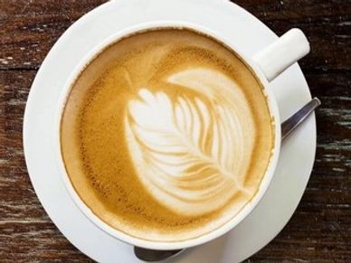 Cup of coffee with latte art on a rustic wooden table.