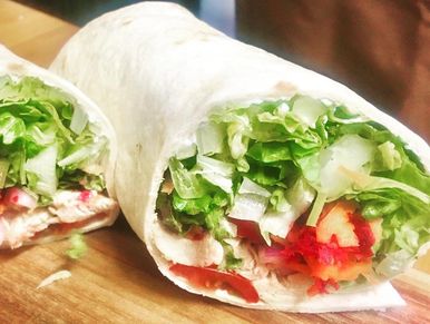 Two fresh wraps filled with lettuce and vegetables on a wooden board.
