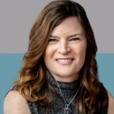 Smiling woman with wavy brown hair against a two-tone background.