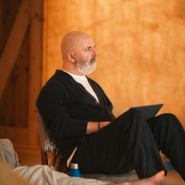 A man with a beard sitting and holding a tablet.