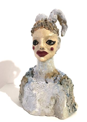 a figuartive ceramic sculpture with a painted face and turned down horns