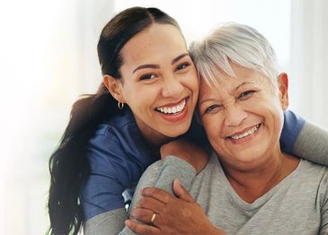 Two women hugging and smiling warmly.