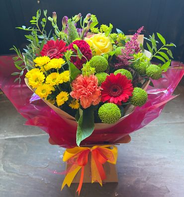Colorful mixed flower bouquet wrapped with vibrant ribbons.