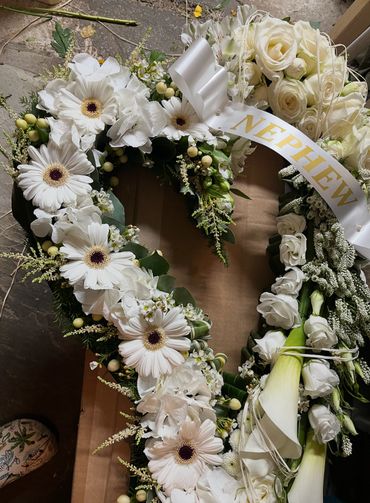 Elegant white floral wreath with a 'NEPHEW' ribbon.
