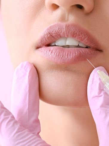 Close-up of lip injection procedure with needle and gloves.