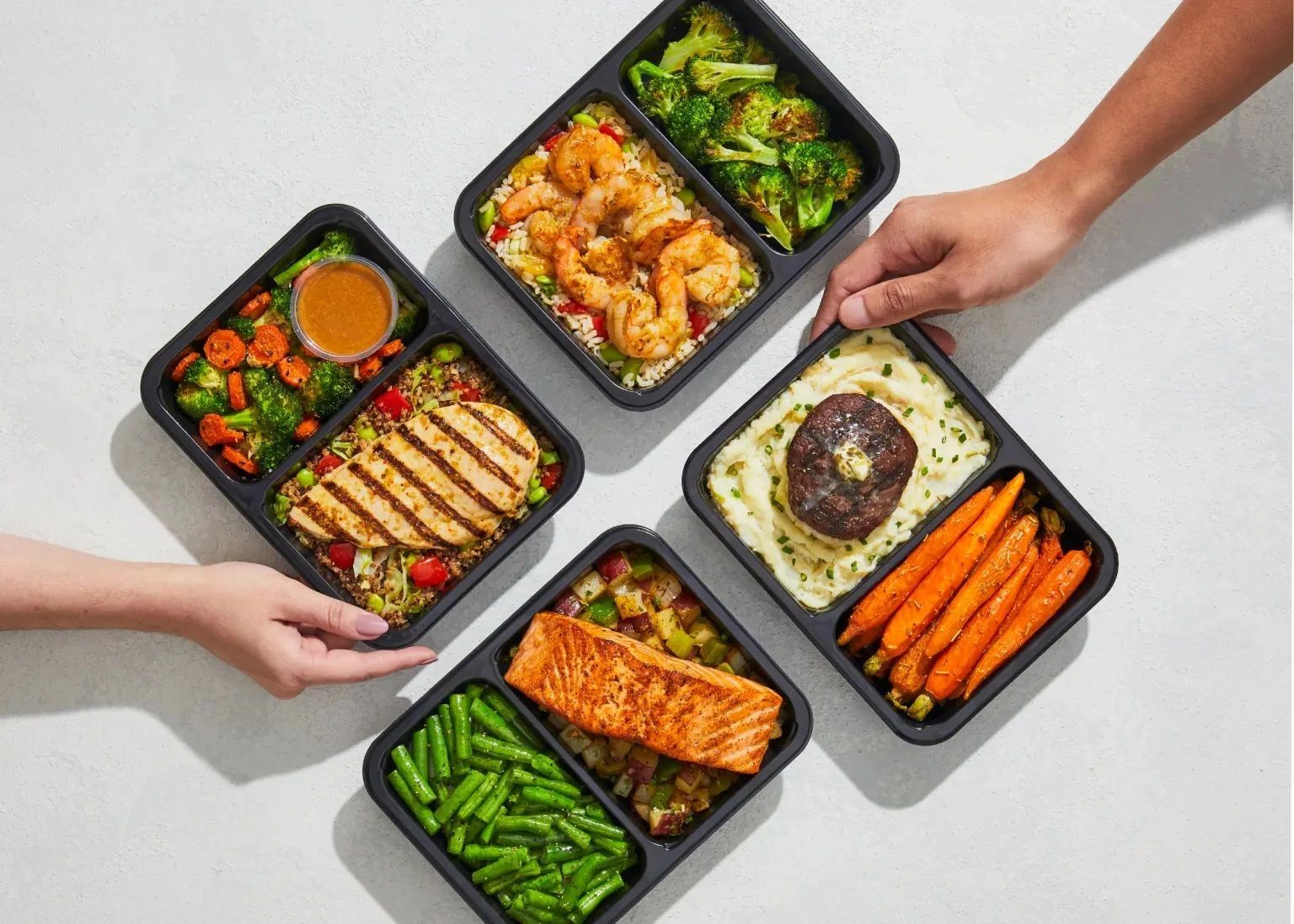 Four healthy meal prep containers with grilled meats and vegetables.
