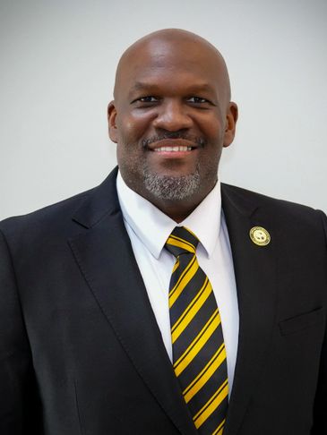 Smiling man in a suit with a striped yellow and black tie.