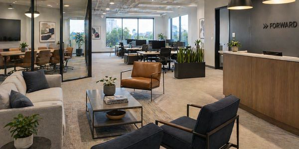 Modern office lounge area with seating and workspaces in the background.