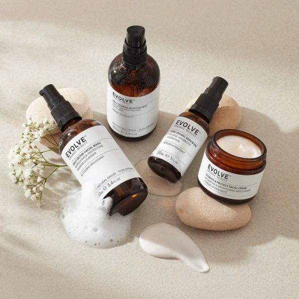 Evolve skincare products arranged with foam, cream, and decorative stones.