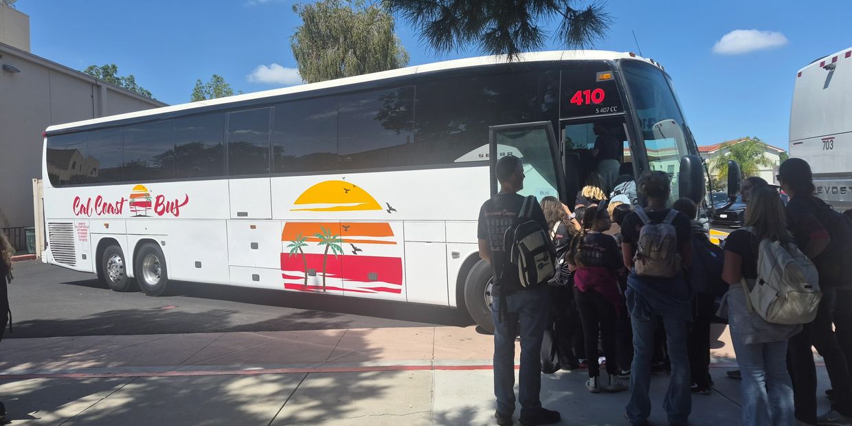 A group boarding a Cal Coast Bus on a sunny day.