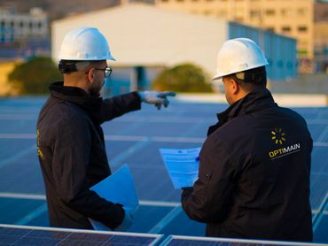 engineers wearing helmets are standing in front of a pv system and looking away