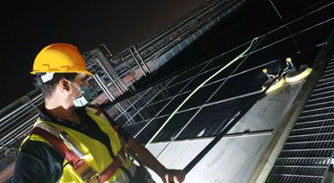 a worker wearing helmet and vest cleaning pv solar panel
