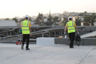 engineers wearing helmets and vests and walking towards pv system