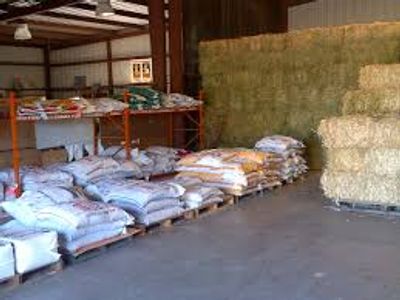 Bags of feed and stacked hay bales in a barn.