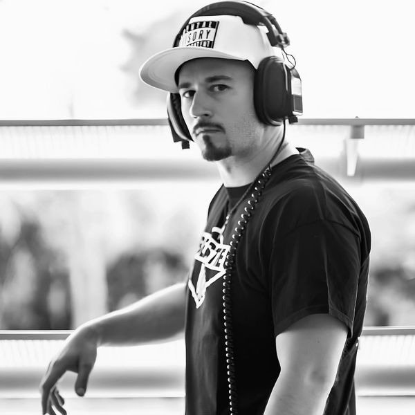 Man wearing headphones and a cap, looking serious.