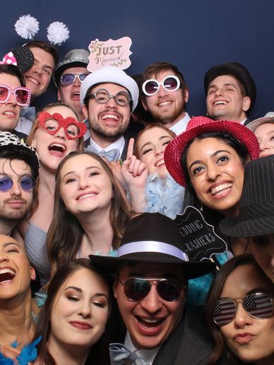 Large group of multiethnic people smiling and laughing, with photobooth props