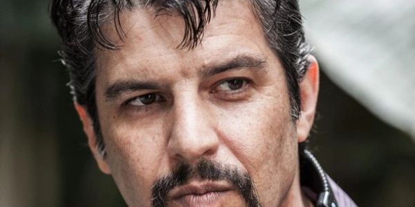 Close-up of a thoughtful man with dark hair and a goatee beard.