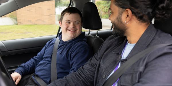 Two people sitting in a car smiling at each other.