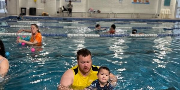 Man and child swimming in an indoor pool.
