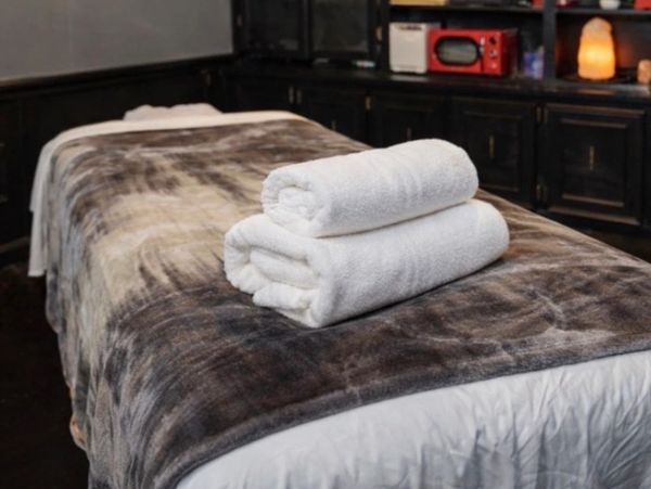A massage table with two neatly folded white towels.