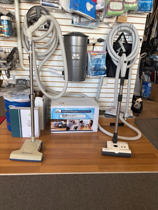 Central vacuum attachment kit displayed with hoses and brushes in a store.