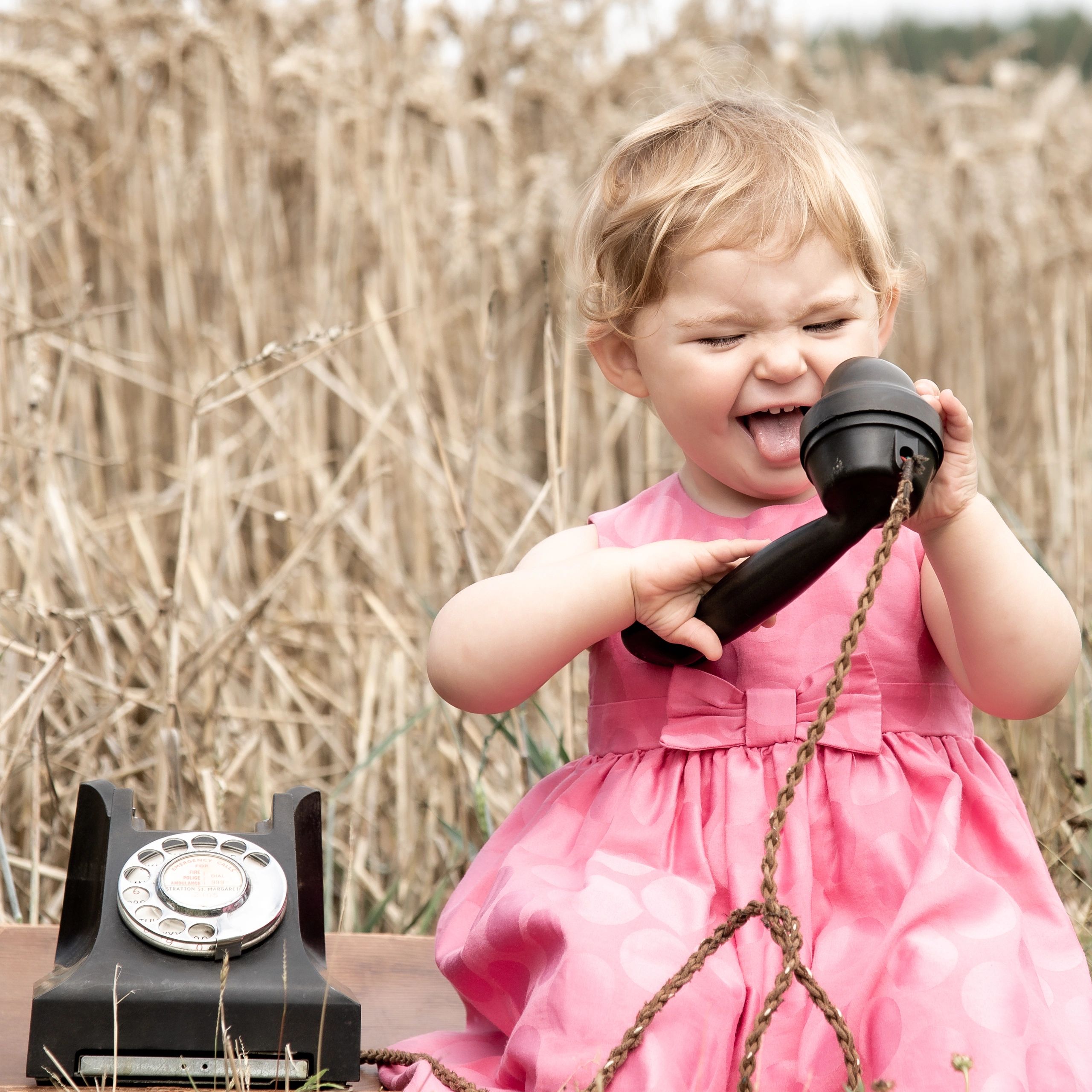 Wedding candid photograph, quirky but fun.  Photograph of a toddler sat in a wheat field on a suitca