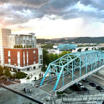 Blue steel bridge over river with people walking and biking during sunset.