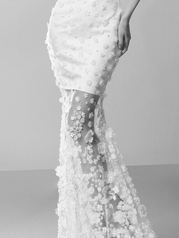 Bride wearing short wedding gown with sheer floor-length overlay with floral embellishment.