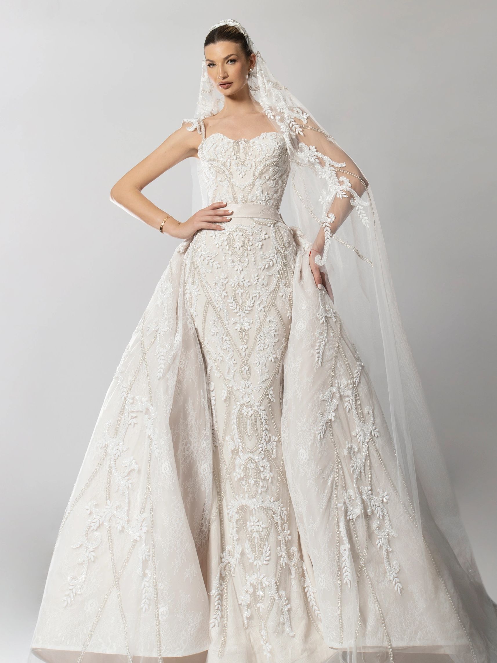 Bride wearing couture wedding gown with hands in hips.