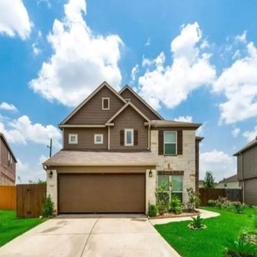 Modern two-story house with brown garage door and green lawn under a blue sky.