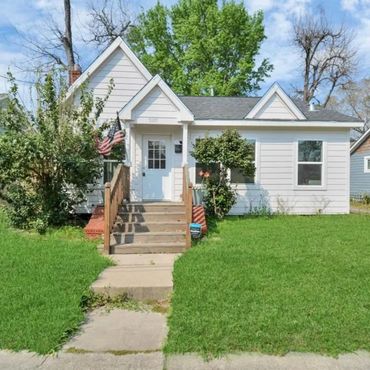 Small white house with a green lawn and an American flag.