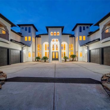 Modern luxury mansion with illuminated windows at dusk.