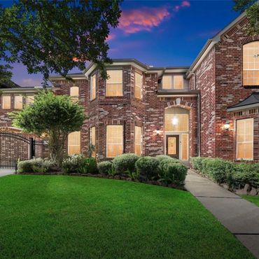 Elegant two-story brick house with well-maintained lawn at twilight.