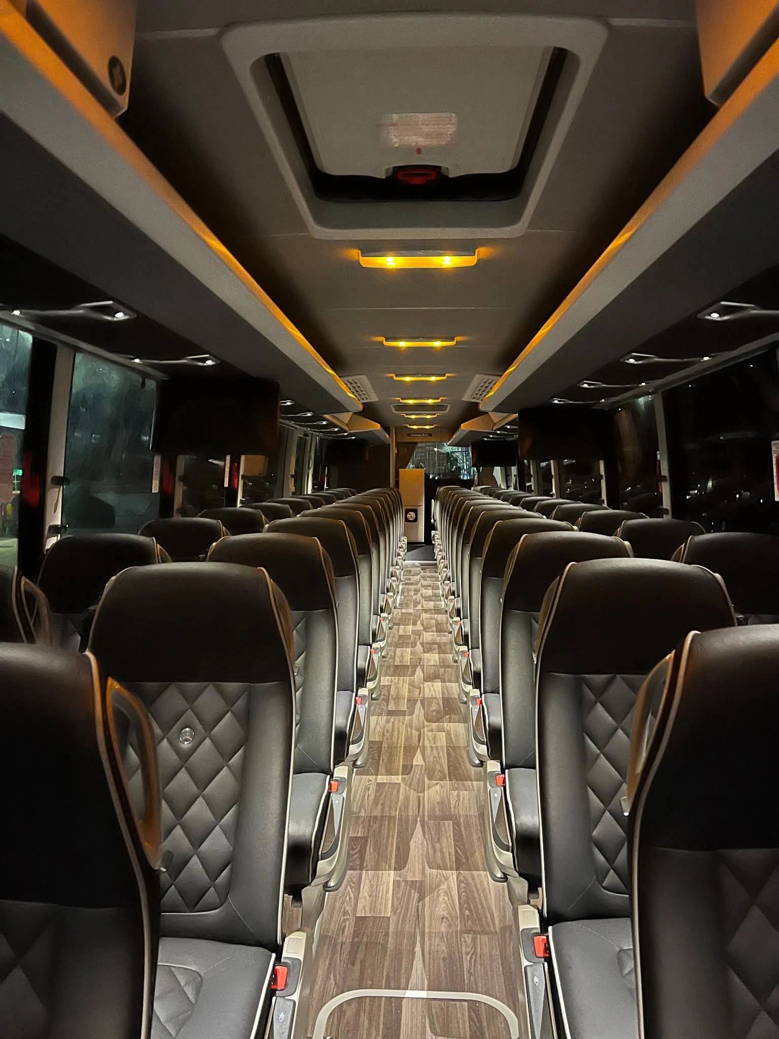 Interior of a modern, empty luxury coach bus with leather seats and wooden flooring.