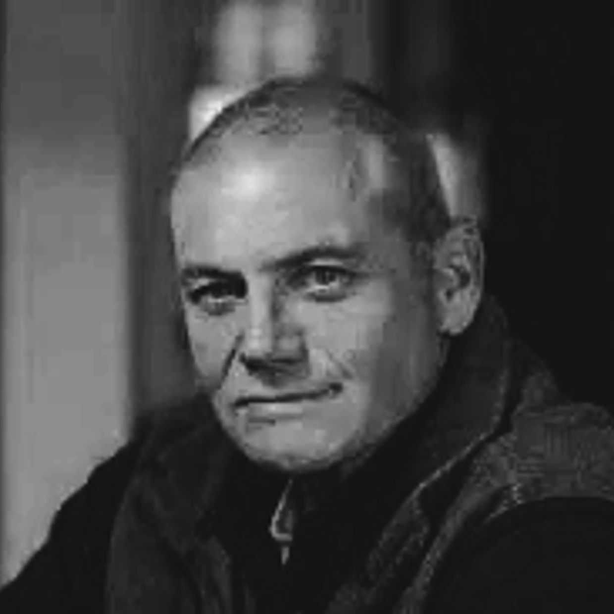 Black and white portrait of a serious man with a bald head.