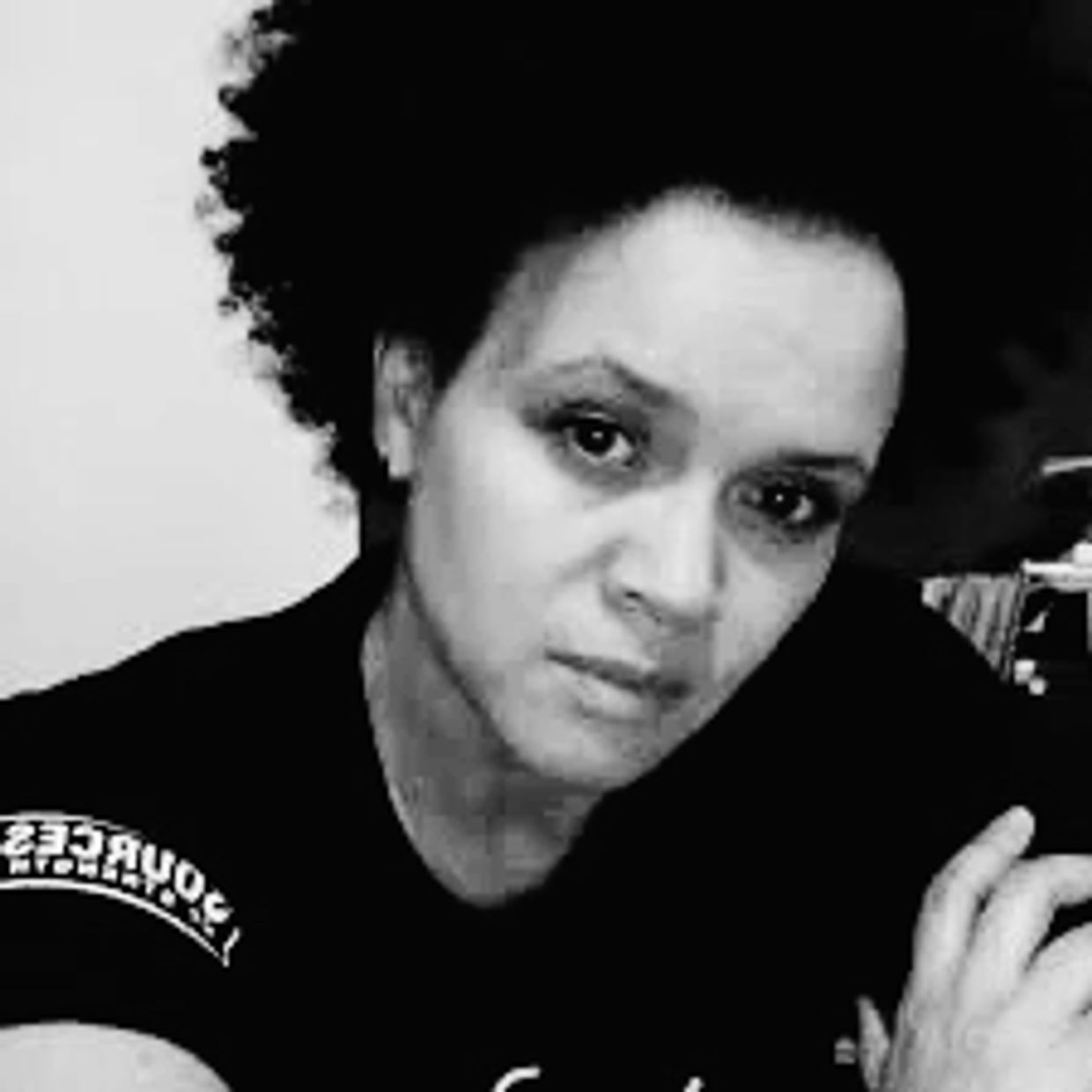 Black and white portrait of a woman with curly hair looking directly at the camera.