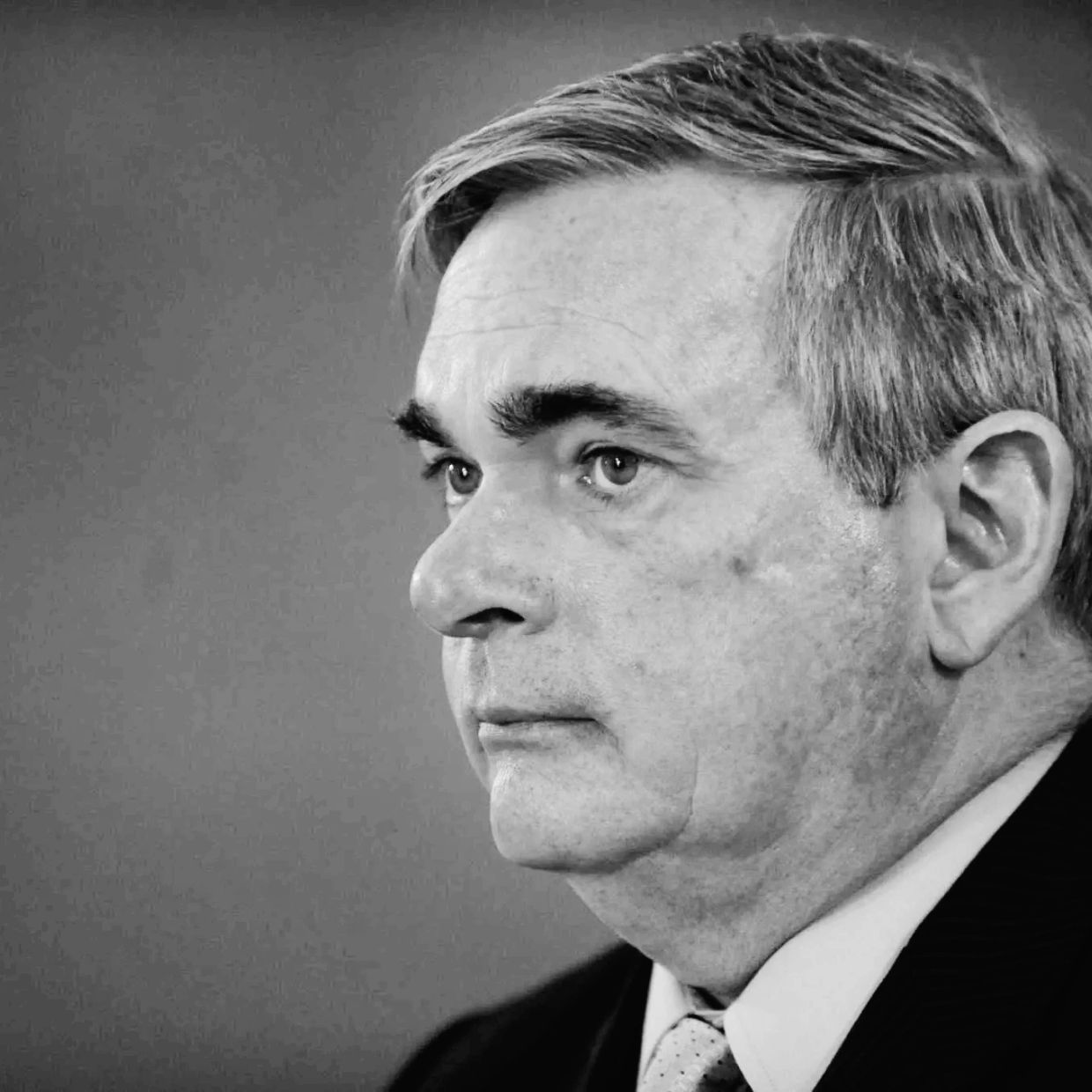 Black and white profile portrait of a serious middle-aged man in a suit.