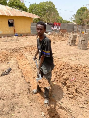 Young man digging a trench with a shovel in a rural area.