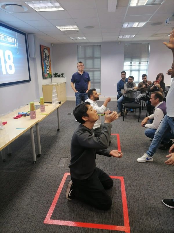 People in an office playing a drinking game with straws on the floor.
