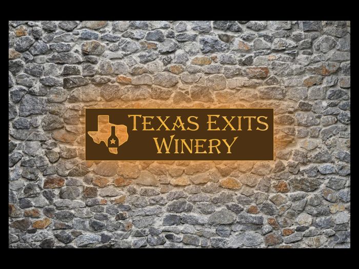 Sign for Texas Exits Winery on a stone wall.