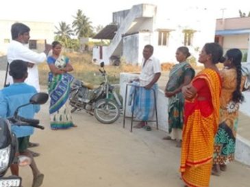 People gathered outdoors in a village setting.