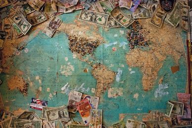 A picture of world map with money on top of it.