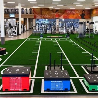 Modern gym with functional training turf and exercise equipment.