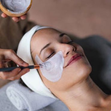 A woman enjoys a facial mask treatment at a spa.